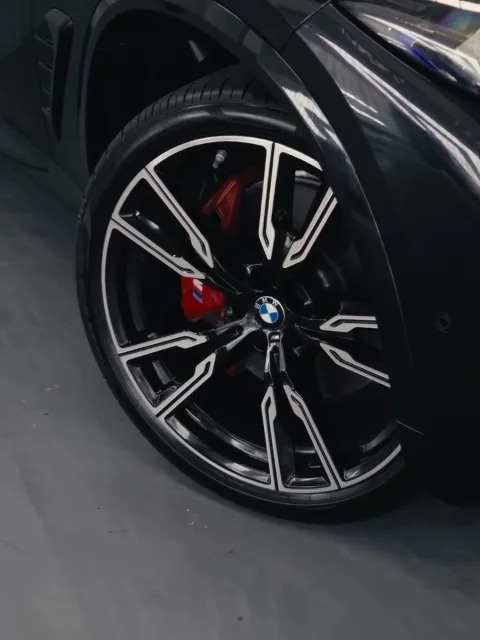 BMW X5 M wheel with a red brake caliper at OFJ Automotive