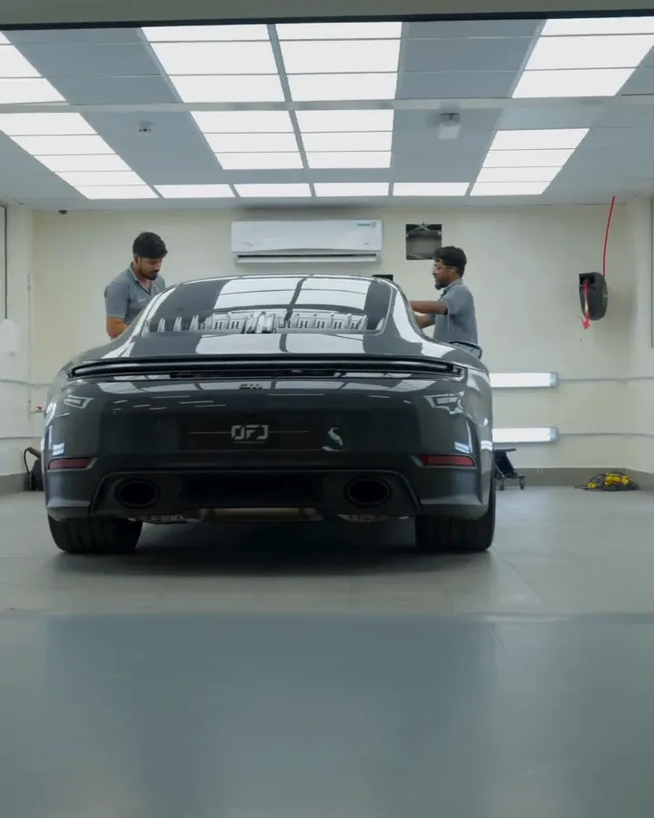 Two OFJ technicians working on a grey Porsche 911 in the bodyshop, Al Quoz, Dubai