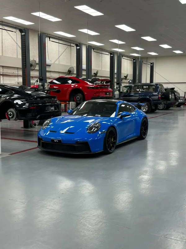 Blue Porsche 911 GT3 in front of cars on the lifts at OFJ Automotive