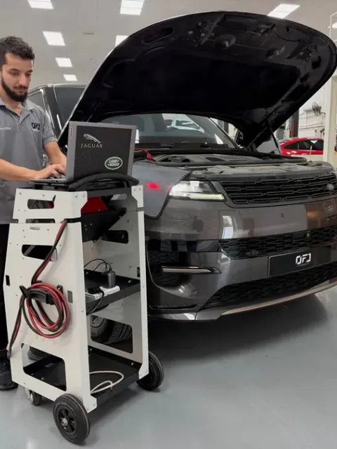 OFJ technician running diagnostics on a Range Rover with a laptop and diagnostic cart